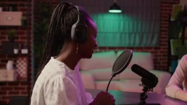 Profesyonel mikrofon kullanarak gülümseyen bir radyo sunucusuyla röportaj yapan Afrikalı bir Amerikalı.