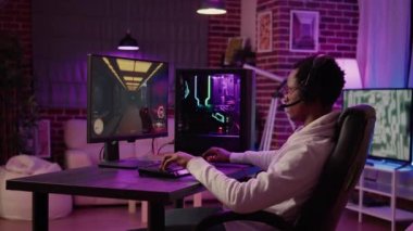 Afrikalı Amerikalı adam bilgisayar oyunu kurulumunu kullanıyor rahatlatmak için çok oyunculu online aksiyon oyunu oynuyor ve takımla konuşuyor.