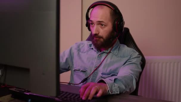 Primer plano del hombre con auriculares de juegos jugando multijugador juego de acción en línea juego de streaming — Vídeos de Stock