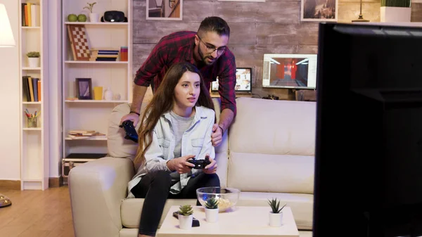 Boyfriend helping his girlfriend to win at video games — Stock Photo, Image