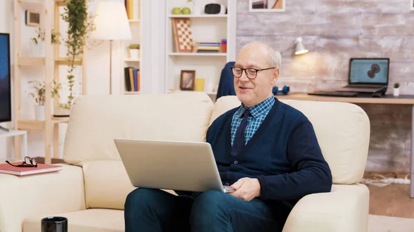 Coppia di anziani con occhiali seduti sul divano durante una videochiamata sul computer portatile . — Foto Stock