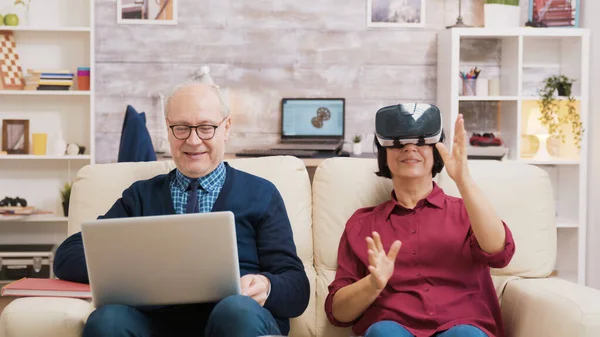 Starší žena sedící na pohovce v brýlích virtuální reality — Stock fotografie