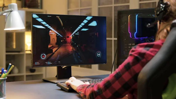 Жінка з навушниками, сидячи на ігровому кріслі, грає у відеоігри на комп'ютері — стокове фото