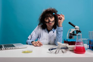 Aptal görünüşlü biyokimyacı elinde cam test tüpleriyle bilinmeyen sıvı maddeler tutuyor.