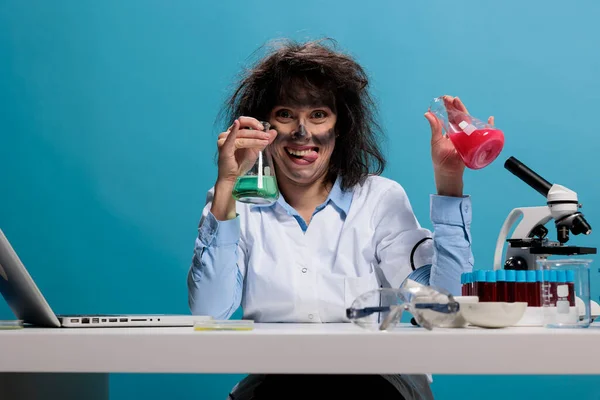 Foolish scientist with funny face expression handling beakers filled with serum. — 스톡 사진