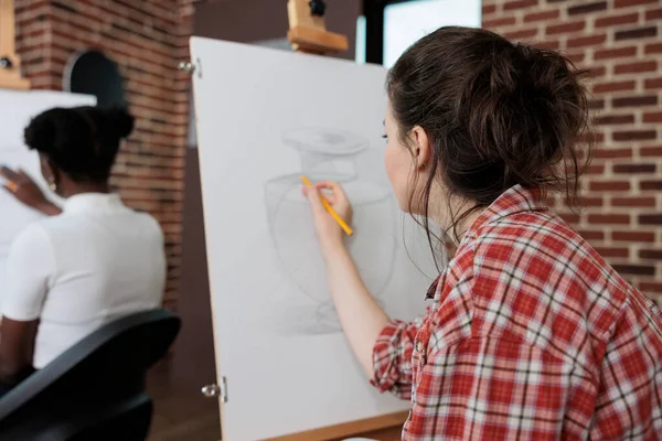 Painter woman drawing artistic vase on white canvas — Stockfoto