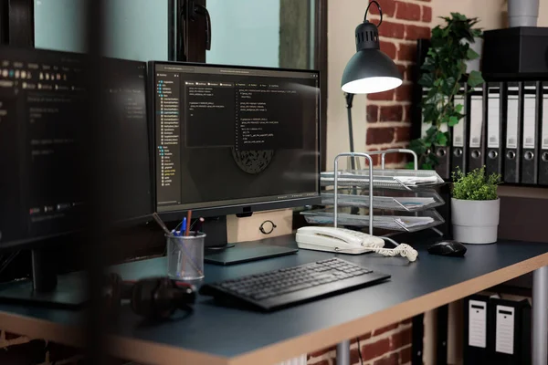 Empty office with nobody in it containing multiple displays showing system programming language. Image of two computer screens displaying software data information and integrated algorithms. — Zdjęcie stockowe