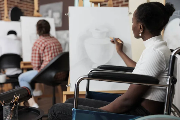 Estudante paralítico em cadeira de rodas que se senta no vaso de desenho de curso artístico — Fotografia de Stock