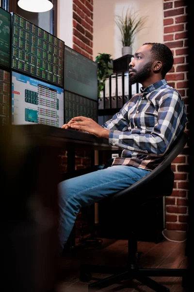 Gerçek zamanlı finansal verileri görselleştirirken eski bir ticaret ajanı çoklu monitör çalışma istasyonunda oturuyor — Stok fotoğraf