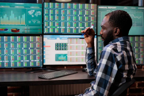 Gözlemci genç yetişkin yatırımcı riskleri düşünürken gerçek zamanlı finansal verileri ve istatistikleri inceliyor.