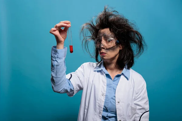Insane anxious looking scientist analyzing chemistry glass tube filled with blood sample. — Stockfoto