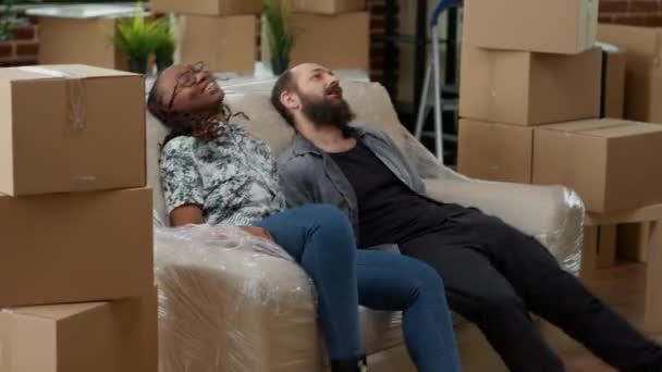 Marido e esposa relaxando no sofá depois de se mudar para casa nova — Vídeo de Stock