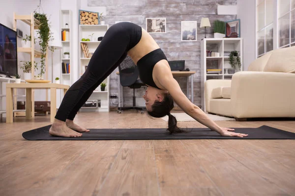 Brunette meisje doet adho mukha svanasana yoga oefening — Stockfoto
