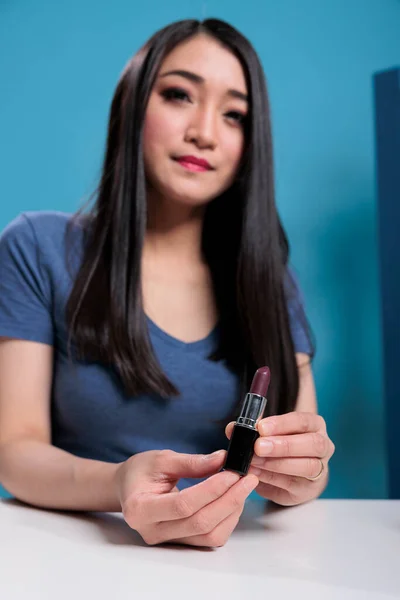 Portrait of attractive vlogger holding lipstick while recording makeup review — Fotografia de Stock