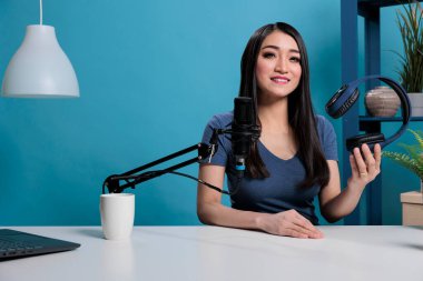 Yayımcı elinde kulaklıkla mikrofona konuşuyor.