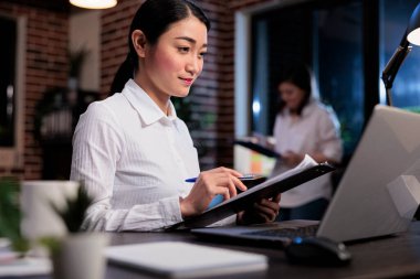Belge panosuyla mali belgeleri inceleyen kendine güvenen bir iş kadını..
