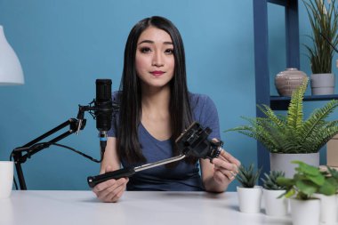 Asyalı vlogger oluşturucu profesyonel tripod tutuyor vlog ürünü gözden geçiriyor