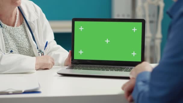 Lekarz i pacjent patrząc na laptopa z wyświetlaczem zielonym — Wideo stockowe