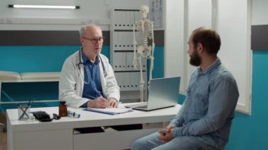 Genç yetişkinlerle sağlık kontrolüne katılan kıdemli doktor.