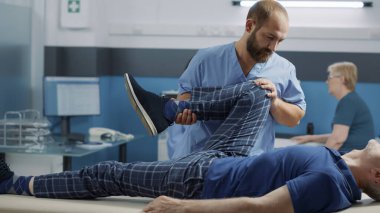 Osteopati uzmanı. Eski hastanın bacak kaslarını esnetiyor.