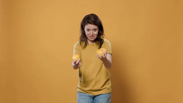 Femme ludique agissant stupide essayant de jongler oranges étant drôle tout en les laissant tomber — Photo