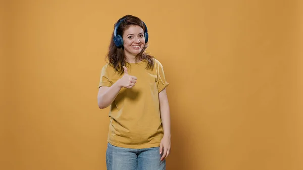 Femme utilisant des écouteurs sans fil pour diffuser de la musique chanson auditive pour la première fois donnant pouces vers le haut — Photo