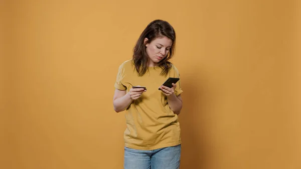 Bored woman doing online shopping holding smartphone having trouble typing credit card — Foto de Stock