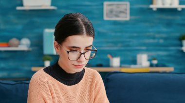 Oturma odasındaki kanepede dizüstü bilgisayar kullanan beyaz adam.