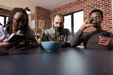 Oturma odasında akıllı telefonlarla oturan bir grup arkadaş..