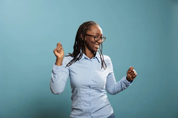 Joyful pleased young woman enjoying dancing and vibing while listening to music playlist on blue background. — 图库照片