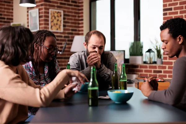 Grupo multicultural de amigos sentados em casa na sala de estar enquanto jogam cartas juntos. — Fotografia de Stock