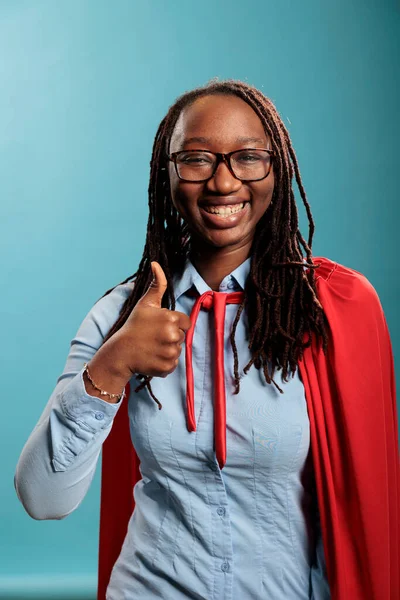 Young adult brave and confident looking superhero woman showing thumbs up gesture to camera. — Stock Photo, Image