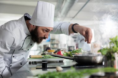 Baş aşçı tavada gurme yemeği pişirirken restorandaki akşam yemeği servisinde servis ediliyor..