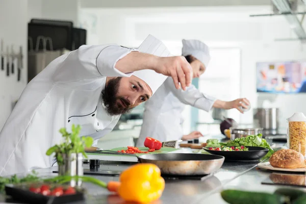 Cocinero de cocina gourmet decorando plato de cena con pimiento rojo mientras cocina comida para un excelente servicio gastronómico en el restaurante. —  Fotos de Stock