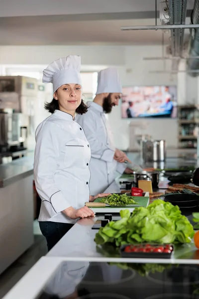 Retrato de la hermosa feliz sous chef de pie en la cocina profesional del restaurante, con uniforme de cocina —  Fotos de Stock