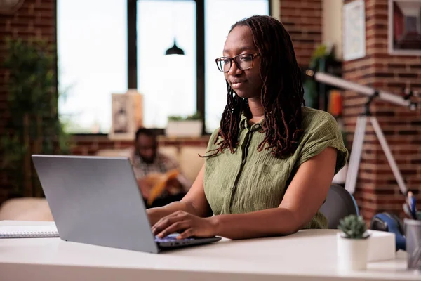 Retrato del freelancer afroamericano que trabaja escribiendo a distancia y mirando la pantalla del ordenador portátil —  Fotos de Stock