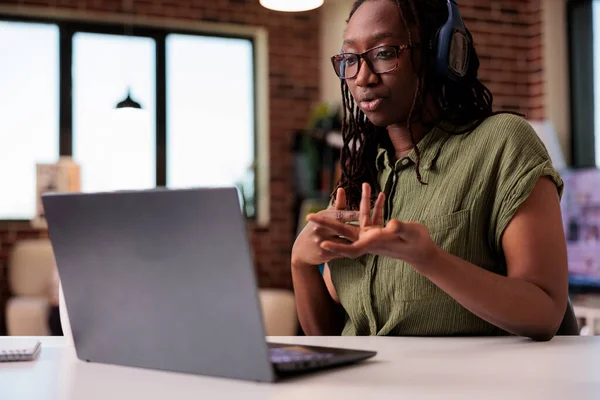 African american student attending webinar talking and gesturing in front of laptop screen while studying — стоковое фото