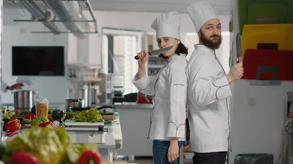 Retrato del equipo de chefs actuando divertido con cuchillos en la cocina del restaurante —  Fotos de Stock