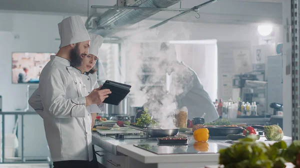 Ομάδα μάγειρες που χρησιμοποιούν ψηφιακή ταμπλέτα για την προετοιμασία αυθεντικό γκουρμέ γεύμα — Φωτογραφία Αρχείου