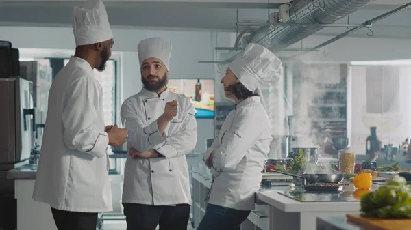 Diverse team of chefs having conversation about cooking dish