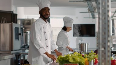 Kamera karşısında kollarını kavuşturarak poz veren kendinden emin bir aşçının portresi.