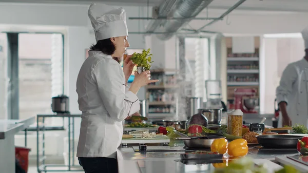 Γυναίκα μαγείρισσα μυρίζει φύλλα δενδρολίβανου για χρήση σε πιάτο τροφίμων — Φωτογραφία Αρχείου