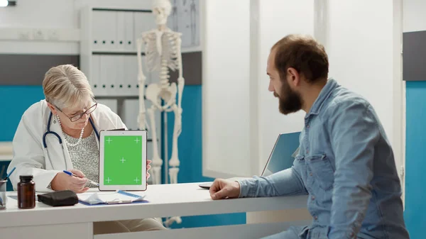 Physician and patient analyzing digital tablet with greenscreen — Stockfoto