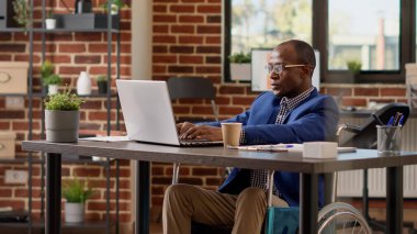 Proje yöneticisi engelli bürosunda dizüstü bilgisayarda rapor hazırlıyor