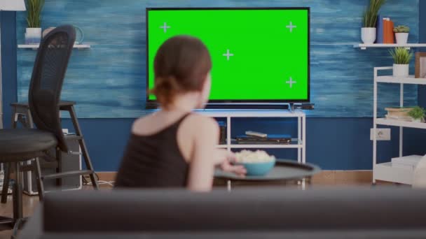 Junge Frau nimmt Imbissschüssel und isst Popcorn, während sie Lieblingsfernsehsendung auf grünem Bildschirm anschaut — Stockvideo