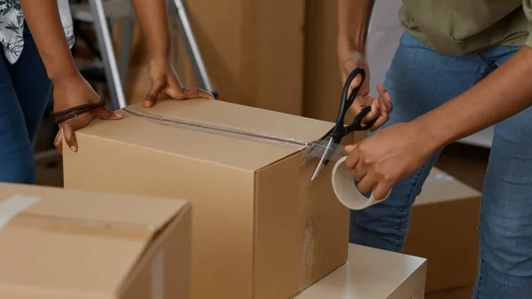 People wrapping up cardboard boxes with sticky tape roller — Stok fotoğraf