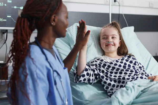 Ziekenhuisverpleegkundige highfive ziek kind terwijl in patiënt behandeling afdeling kamer. — Stockfoto