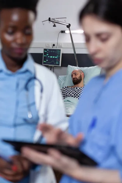 Médecin et infirmière lisant les résultats des tests numériques sur tablette pour homme à faible saturation spo2 — Photo