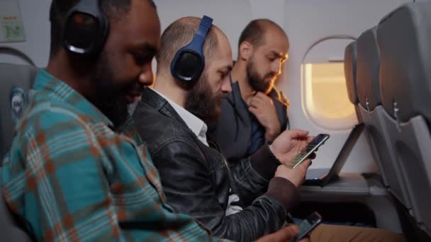 Employé masculin assis à bord d'un avion pendant le coucher du soleil — Video