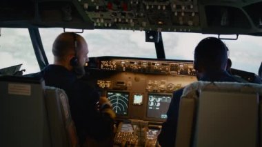 Uçak kaptanı ve yardımcı pilot gösterge panelindeki radar pusulasına bakıyor.